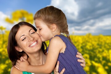 Tender mother and daughter happy together, hugging in nature in a field on a summer day