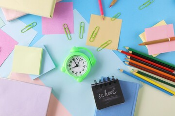 Alarm clock, books and stationery on pastel colors background of colorful paper, back to school, education, student study table, blur focus, copy space, top view