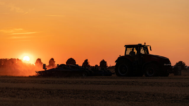 Feldarbeit am Abend: Traktor mit Grubber
