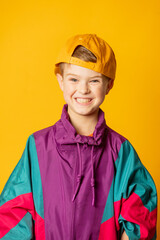 Stylish kid boy in 80s sport suit and cap on yellow background