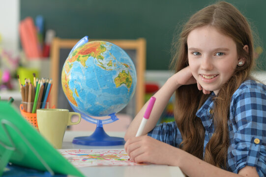 girl siting at table with globe and studying - Powered by Adobe