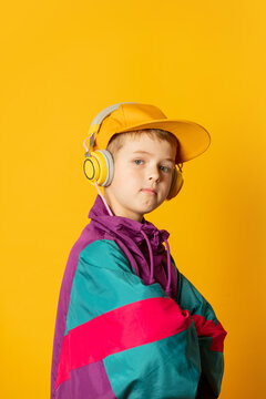 Stylish kid boy in headphones on yellow background