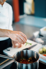 Professional restaurant kitchen, close-up: the chef throws greens into the pan