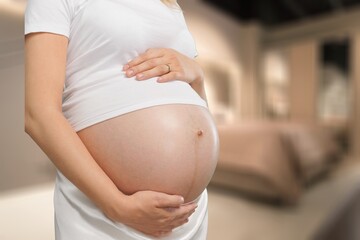 Happy expectant mother feeling kicks, caressing big belly. Pregnant woman. Motherhood, pregnancy concept