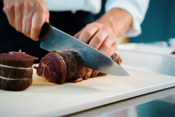 Professional restaurant kitchen, close-up: Chef cut meat for filet mignon before cooking