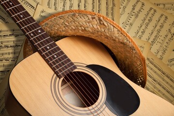 The fretboard of an old vintage acoustic guitar with strings next to sheets of music. A musical...