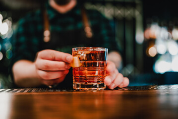 man bartender hand making negroni cocktail. Negroni classic cocktail and gin short drink with sweet vermouth, red bitter liqueur