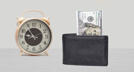 time and money concept. Clock and 100 dollars on the table. Front view
