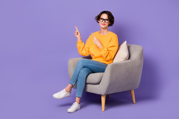 Fototapeta na wymiar Portrait of attractive cheerful girl sitting demonstrating copy space ad isolated over violet lilac color background