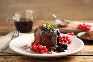 Delicious warm chocolate lava cake with mint and berries on wooden table