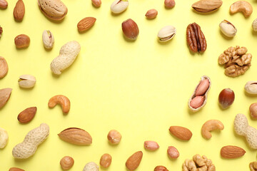 Different delicious nuts on yellow background, flat lay. Space for text