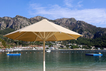 Sun umbrella on sea beach. View to mountains on Mediterranean coast of Turkey, floating pontoons...