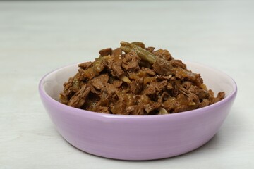 Wet pet food in feeding bowl on white table