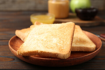 Fototapeta na wymiar Crispy toasts on wooden table, closeup. Delicious breakfast