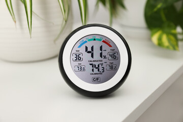 Digital hygrometer with thermometer on white table, closeup - obrazy, fototapety, plakaty