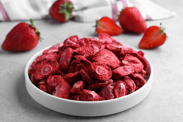 Freeze dried and fresh strawberries on light grey table, closeup