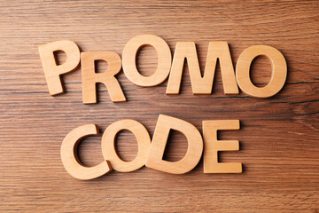Words Promo Code made of wooden letters on table, flat lay