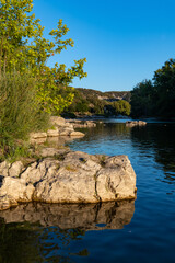 Obraz premium Summer evening in Vallon-Pont-d’Arc in Provence southern France. Ardèche river is popular for vacation, camping and outdoor activities like kayaking, hiking or bathing. Warm sunset atmosphere.