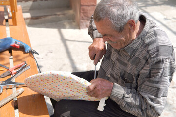 Old man fixing broken chair with screwdriver