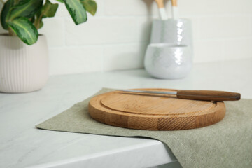 Fototapeta na wymiar Clean towel, wooden cutting board and knife on countertop in kitchen
