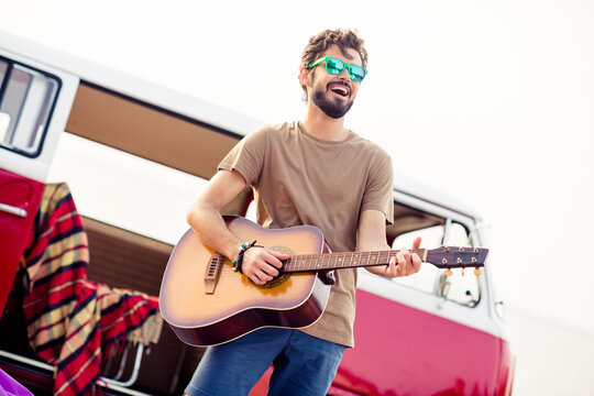 Portrait of overjoyed cheerful handsome guy enjoy playing acoustic guitar have good mood outdoors