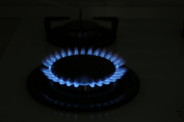 Modern gas cooktop with burning blue flame in kitchen at night