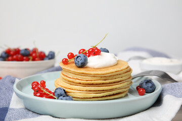 Tasty pancakes with natural yogurt, blueberries and red currants on table