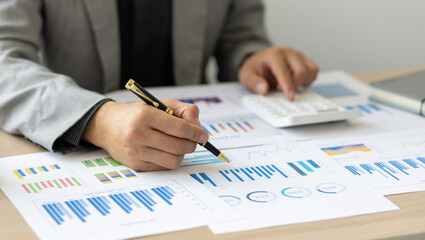 Businessman is analyzing financial documents and business reports using calculating calculator.