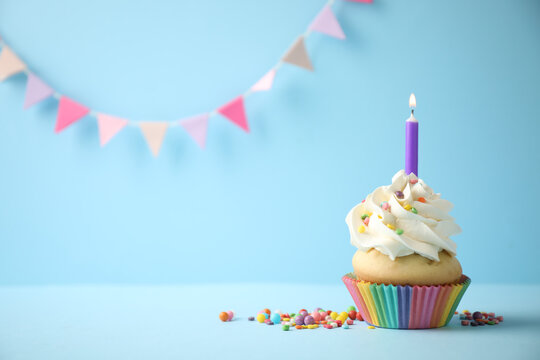 Delicious birthday cupcake with candle on light blue background. Space for text