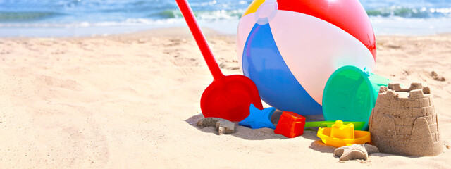 Different sand toys and beach ball near sea, space for text. Banner design