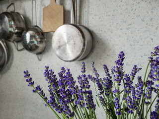 A bouquet of lavender on the background of kitchen utensils hanging on the wall. Colander,...