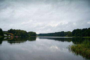 Dramatic landscape at the lake during stormy day. Rainy weather on a pond shore.