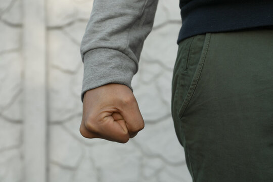 Angry man with clenched fist against white wall, closeup