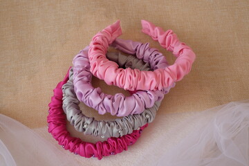Soft pastel color handmade scrunchy or scrunchies headband made out of satin silk fabric texture. A hairband or headpiece with ruffle pattern.
