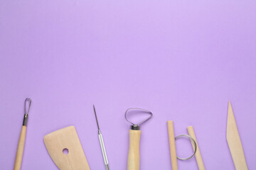 Set of clay modeling tools on violet background, flat lay. Space for text
