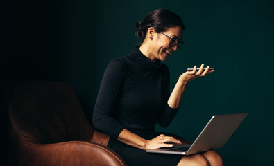 Businesswoman using laptop and mobile phone in office
