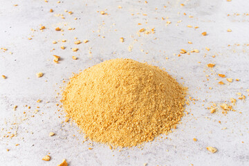 Pile of grinded biscuits and cookie crumbs on light gray background. Crushed biscuits for...