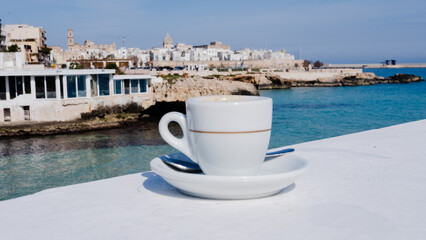 cup of coffee on the bottom view of Monopoli, Puglia. Italy