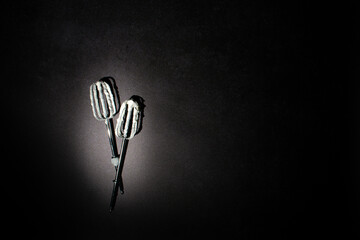 Hand mixer beaters used for whisking white cream cheese filling against black background. Dark...