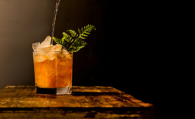 iced tea with crashed ice in a transparent glass isolated over dark black background with space for text or promo, on wooden table top. High quality photo