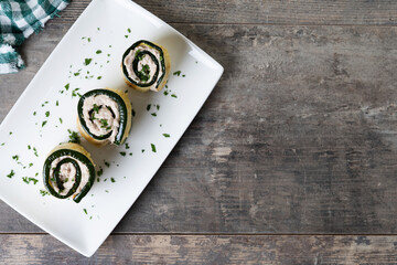 Grilled zucchini rolls with tuna and cream cheese on wooden table. Top view. Copy space