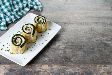 Fototapeta na wymiar Grilled zucchini rolls with tuna and cream cheese on wooden table. Copy space