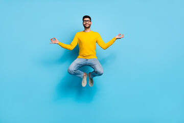 Fototapeta na wymiar Full size photo of carefree positive guy jump meditate closed eyes isolated on blue color background