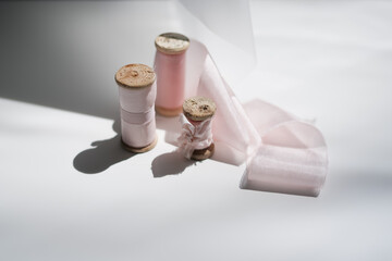Elements for a chic wedding. Silk light pink ribbons in daylight for a bouquet stand on a white background with a decorative light silk ribbon