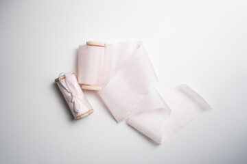 Silk light pink ribbons for a bouquet lie on a white background with a decorative light silk ribbon laid out.