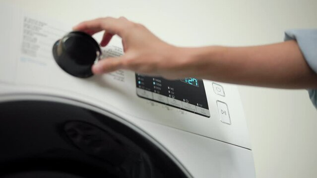 Finger of woman press the switch to make the washing machine work. Home appliances.