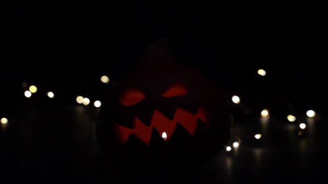 Carved Halloween pumpkin with lights on background. Dark key footage.