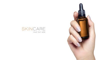 Woman's hand holding a brown glass dropper cosmetic bottle without label. Isolated on white background with copy space. Mock-up for beauty and skincare concept.