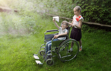 A girl carries a sick boy in a wheelchair