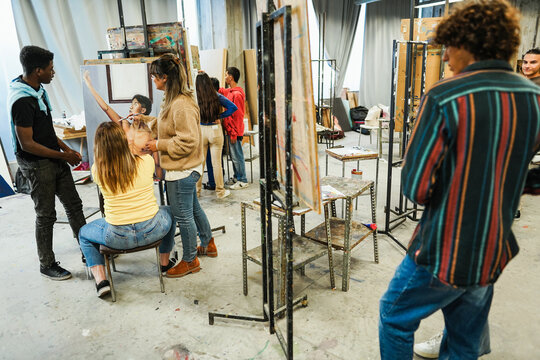 Mature teacher working with art students during painting class at school - Focus on teacher face